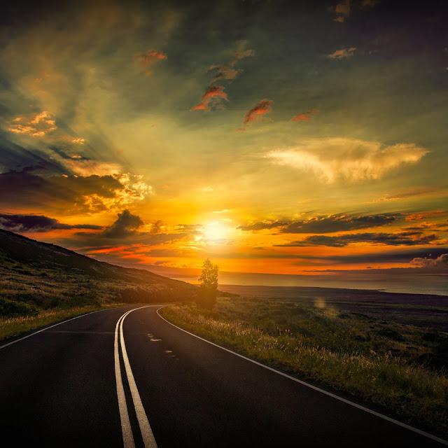 Estrada segue em direção a um pôr do sol dourado