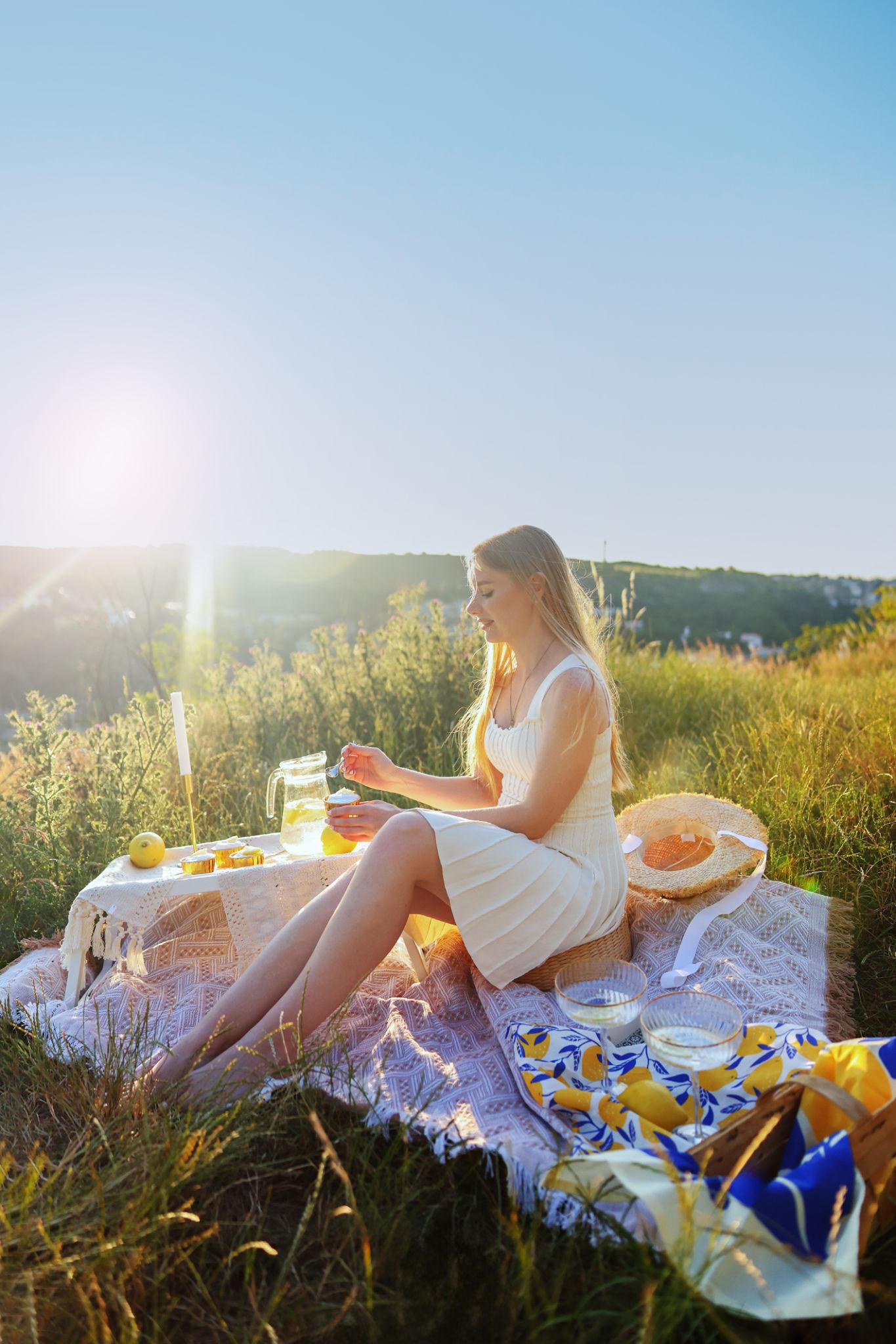 Mulher aproveita um piquenique ao pôr do sol em um campo